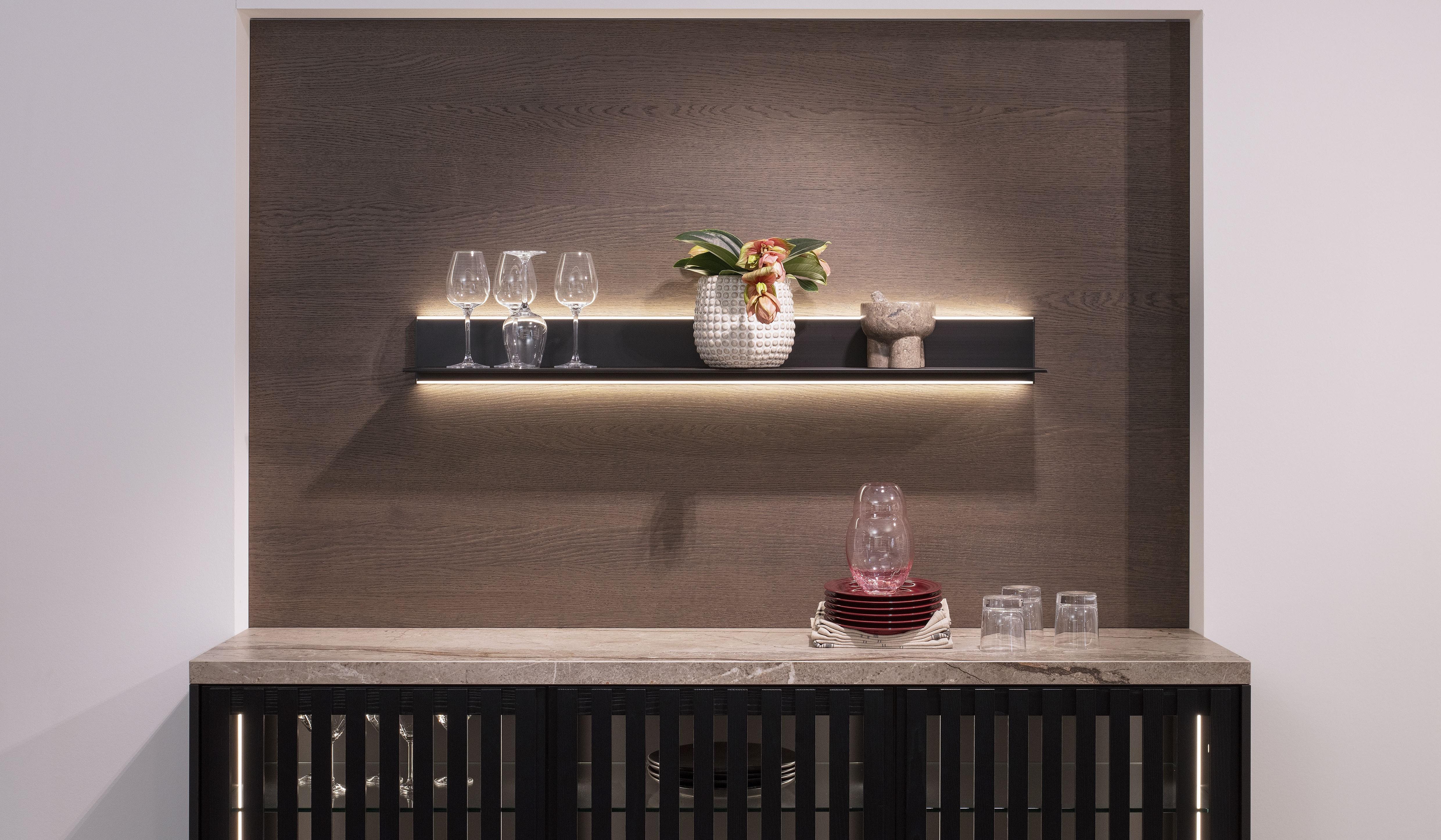 Modernes Regal mit Gläsern, einer Karaffe und einer Blumenvase auf beleuchtetem Holzbrett.