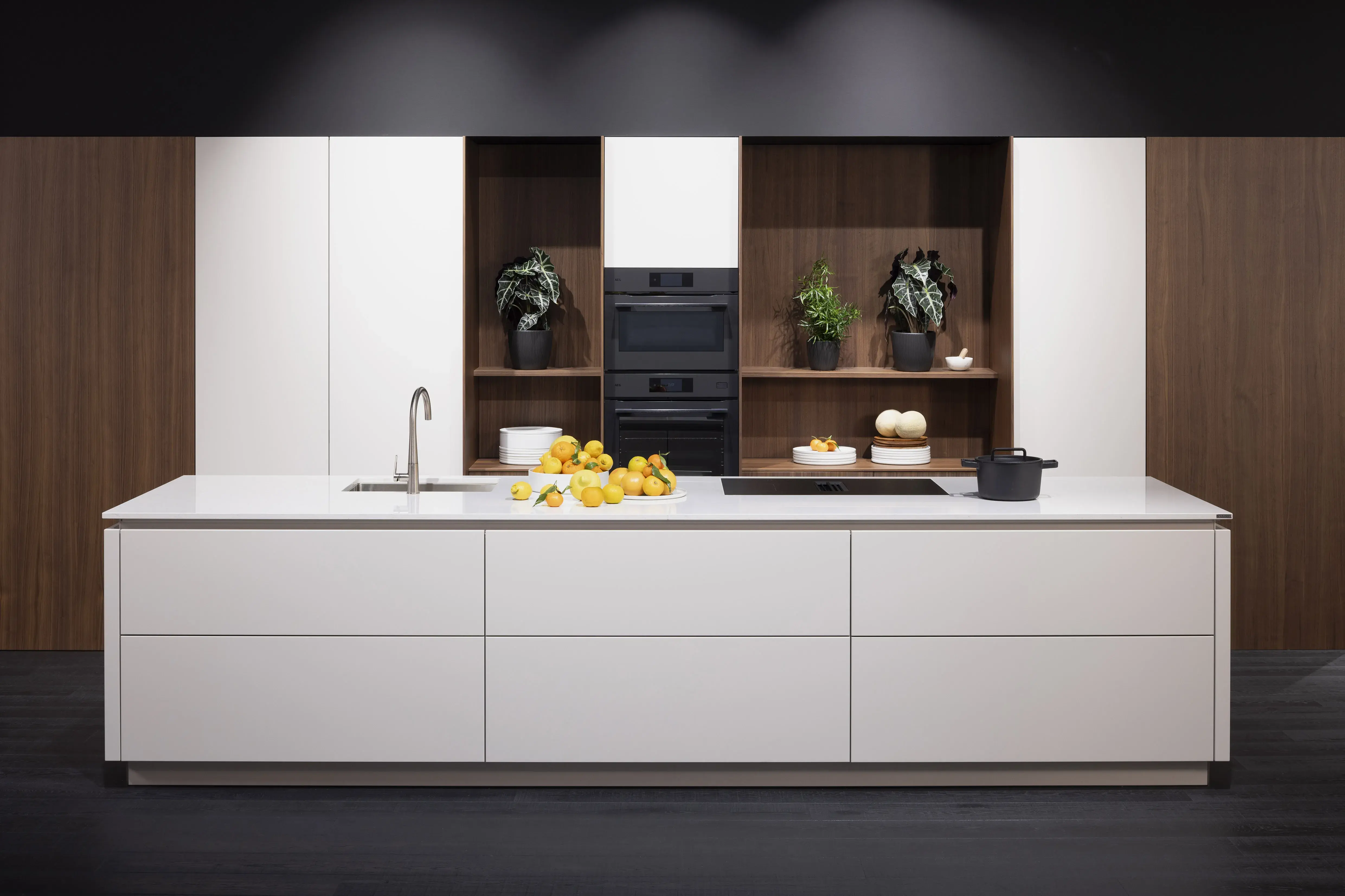 Moderne Küche mit weißer Kochinsel, Zitronen, Wasserhahn und Holzregalen im Hintergrund.