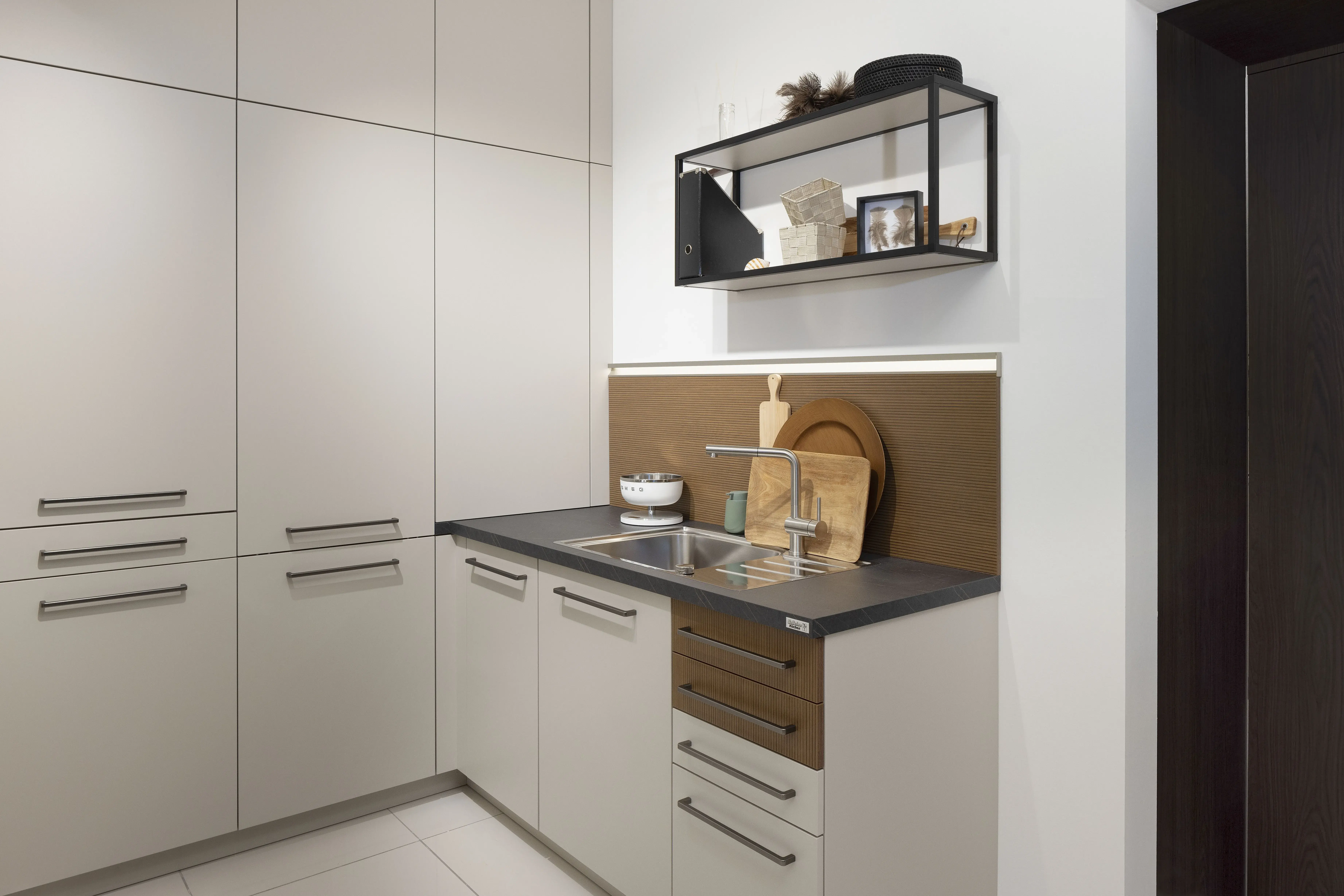 Moderne weiße Küche mit Spüle, Hängeregal und Holzdekor.