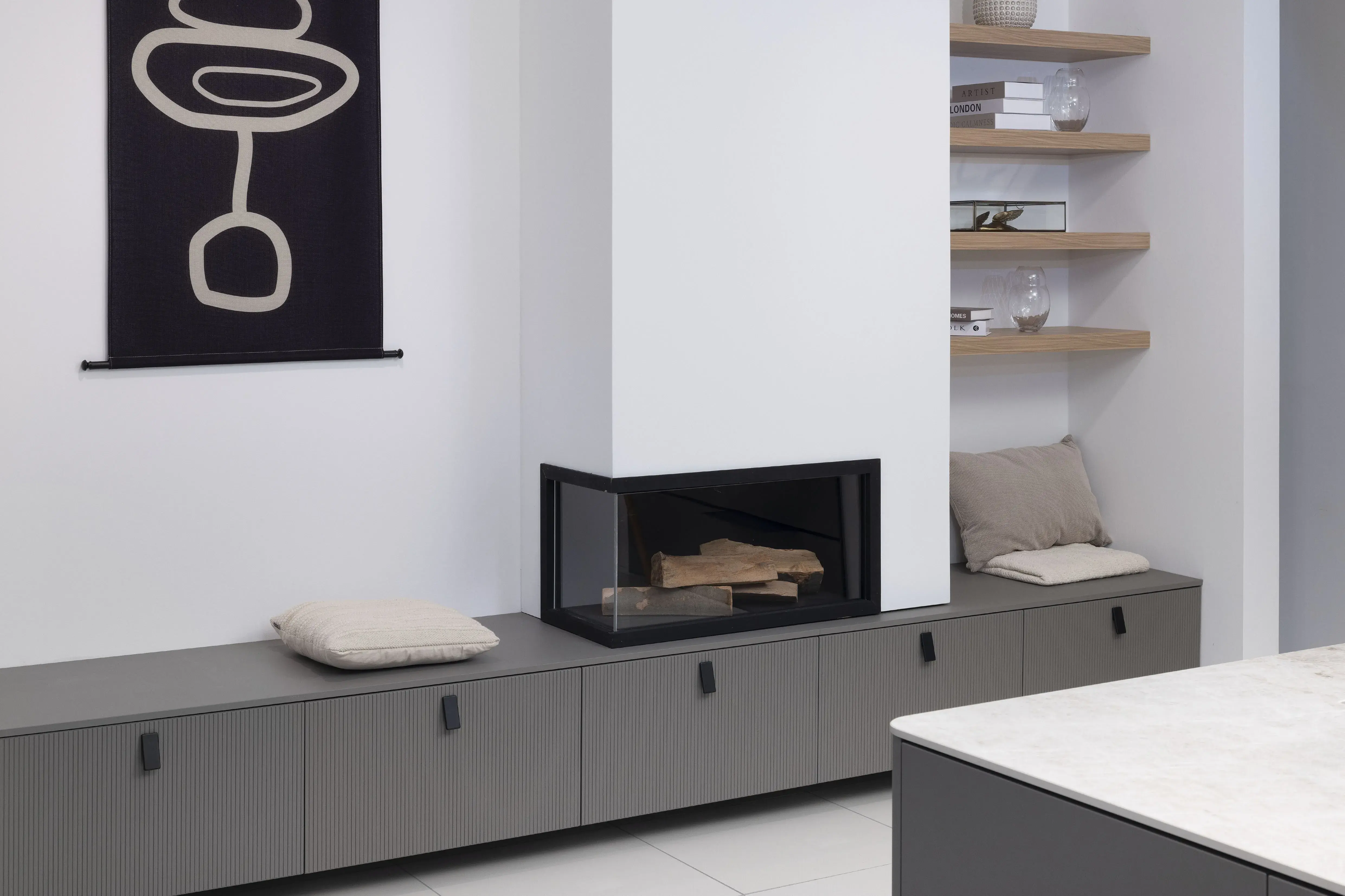 Modernes Wohnzimmer mit Kamin, grauen Schränken, Kissen und Wandregalen.